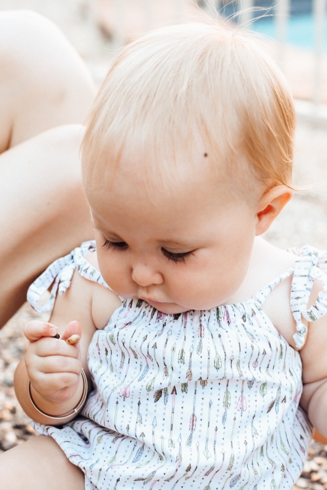 Маленькая светловолосая девочка сидит на песке