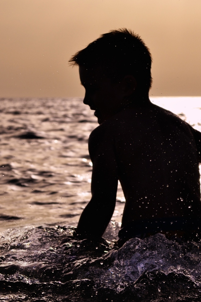 Маленький мальчик купается в воде летом