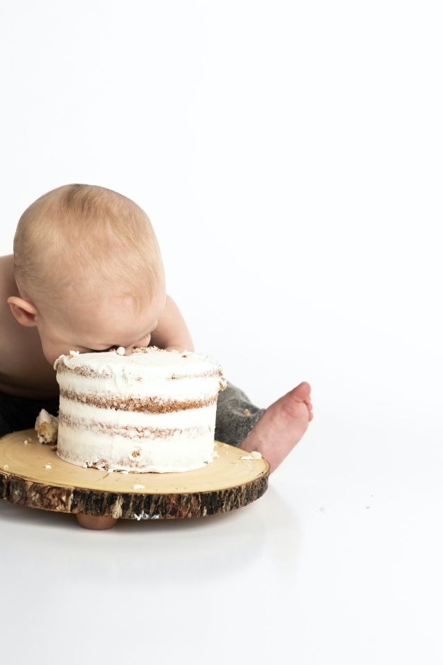 Маленький мальчик ест праздничный торт на белом фоне