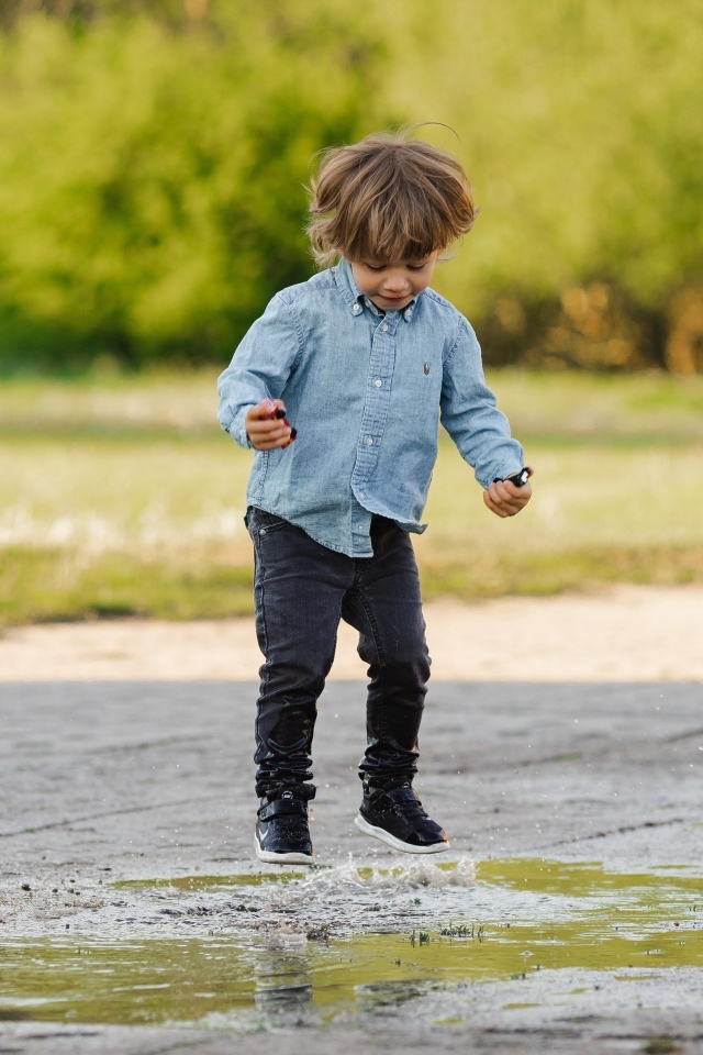 Маленький  мальчик прыгает по лужам