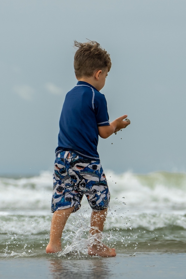 Маленький мальчик гуляет по морскому берегу