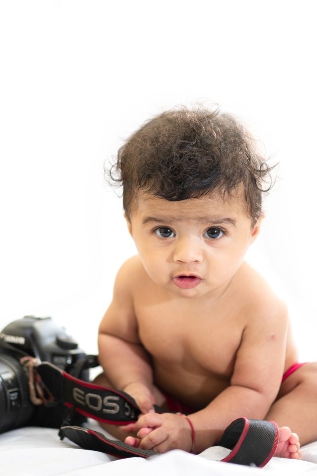 Маленький мальчик с фотоаппаратом на белом фоне