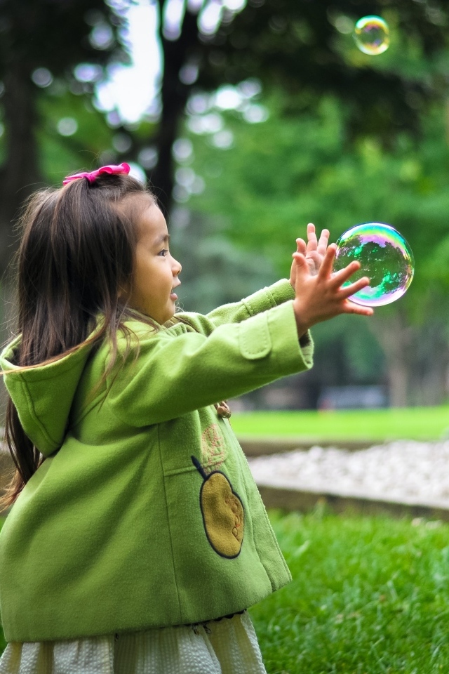 Маленькая девочка ловит мыльные пузыри