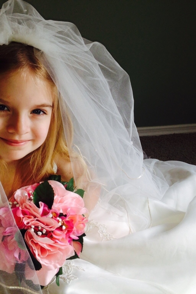 Маленькая девочка в костюме невесты с букетом