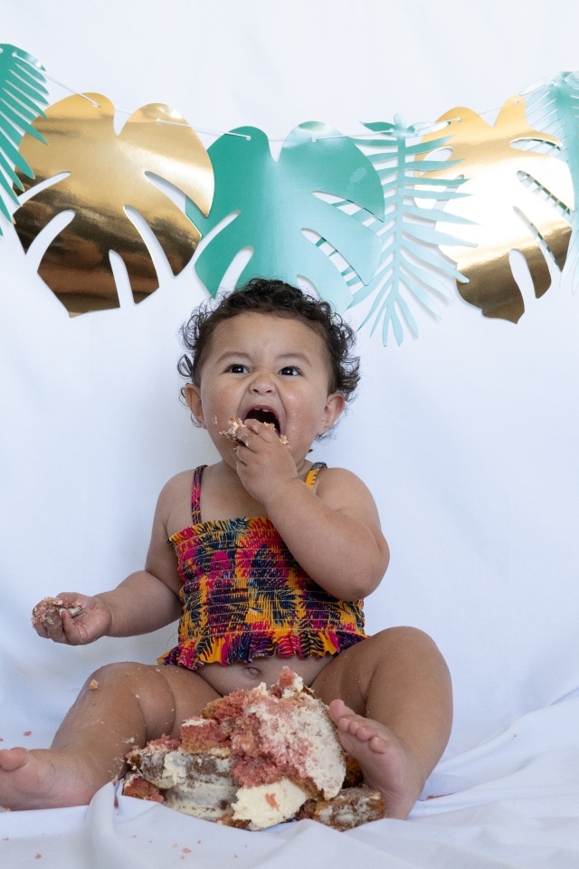 Маленькая девочка ест торт на белом фоне