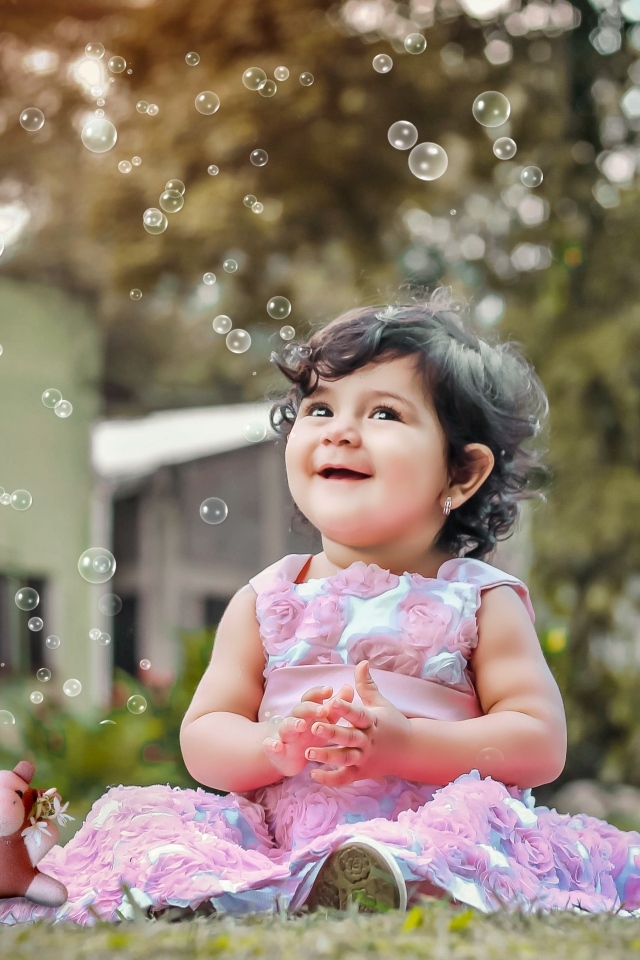 Маленькая девочка радуется мыльным пузырям