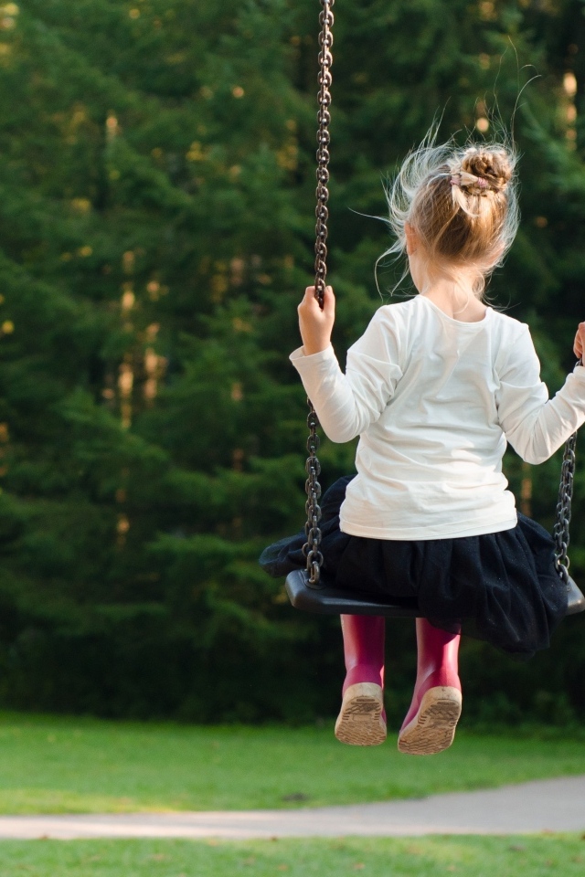 Маленькая девочка катается на качели