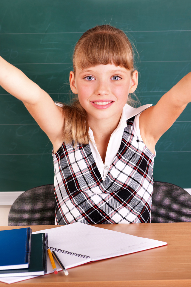 Маленькая девочка школьница в классе за партой 