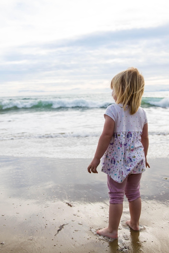 Маленькая девочка стоит на берегу моря