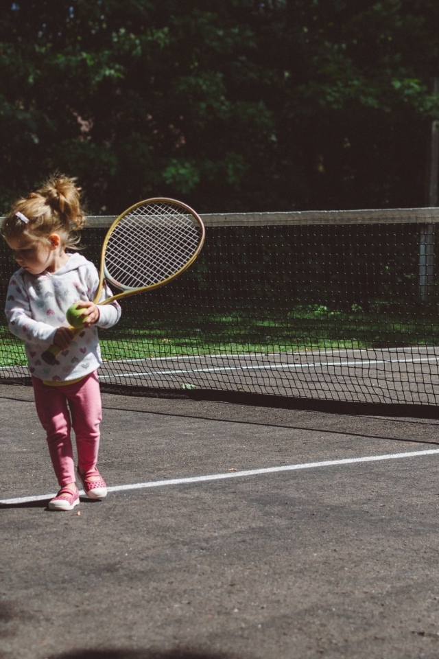 Маленькая девочка с ракеткой на поле