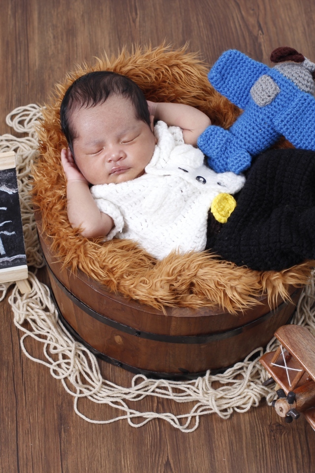 Маленький новорожденный малыш спит в бочке 