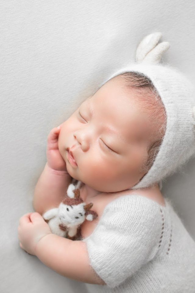 Маленький спящий малыш на сером фоне