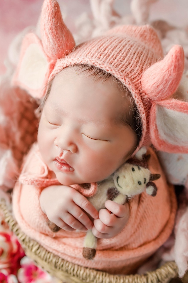 Маленький спящий новорожденный ребенок в шапке с рогами