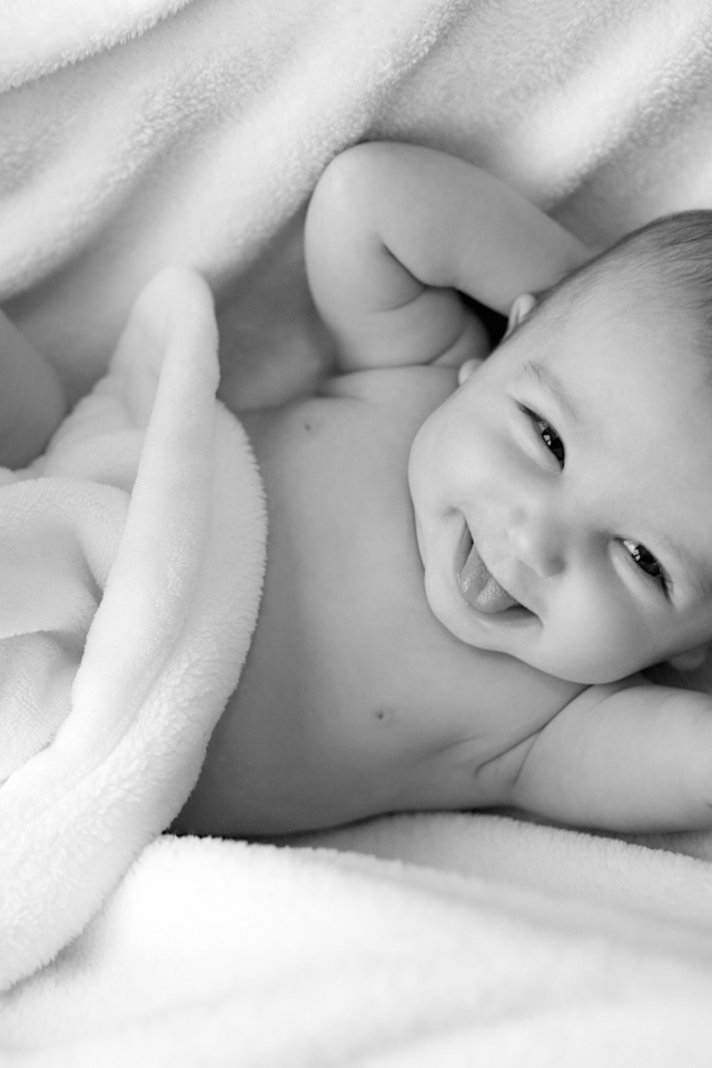 Маленький улыбающийся ребенок в белом покрывале