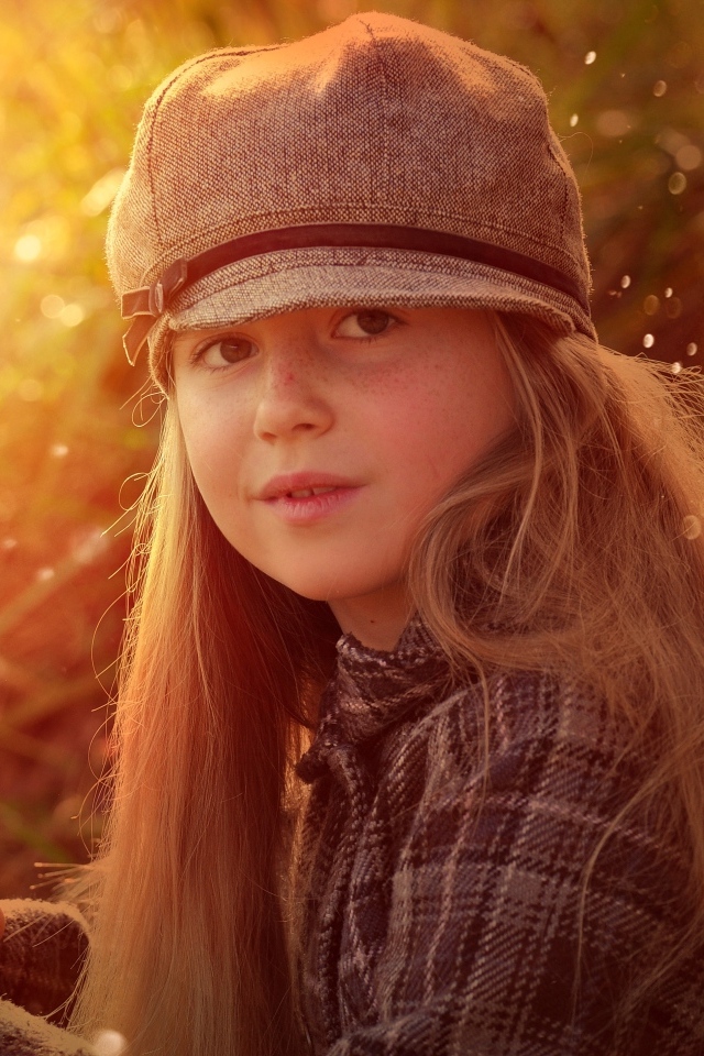 Длинноволосая девочка в кепке в лучах солнца
