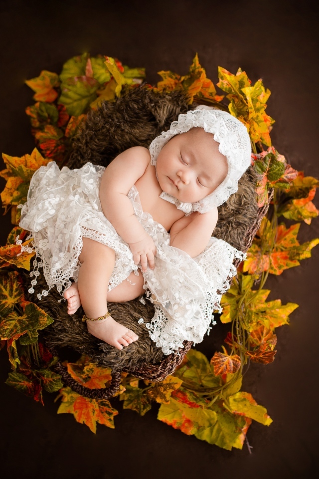 Новорожденная девочка в колыбели в белом костюме