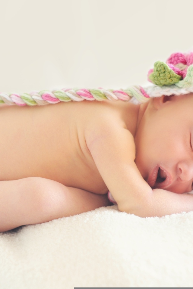Новорожденная девочка спит в шапке