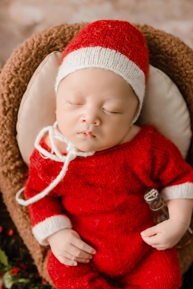 Новорожденный малыш в красном вязаном костюме