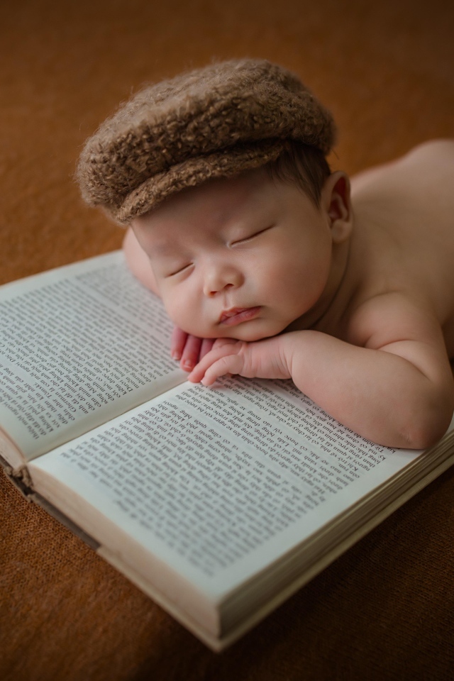 Новорожденный малыш спит на книге