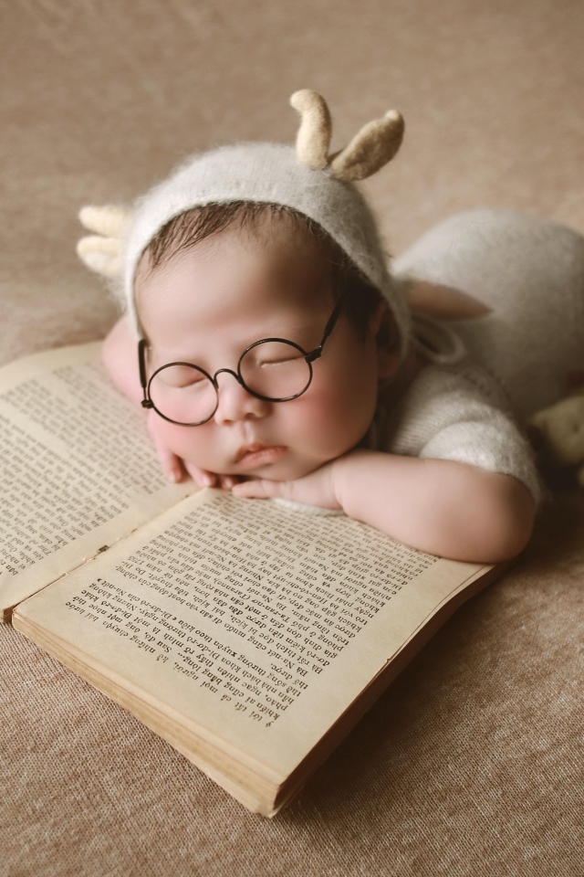 Новорожденный ребенок спит с книгой