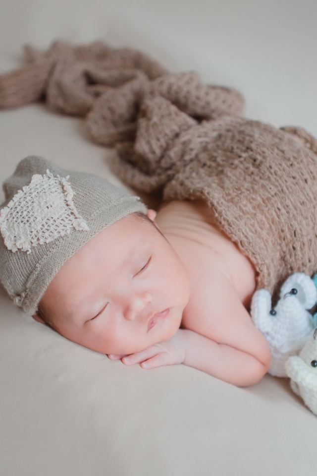 Новорожденный малыш спит на сером покрывале