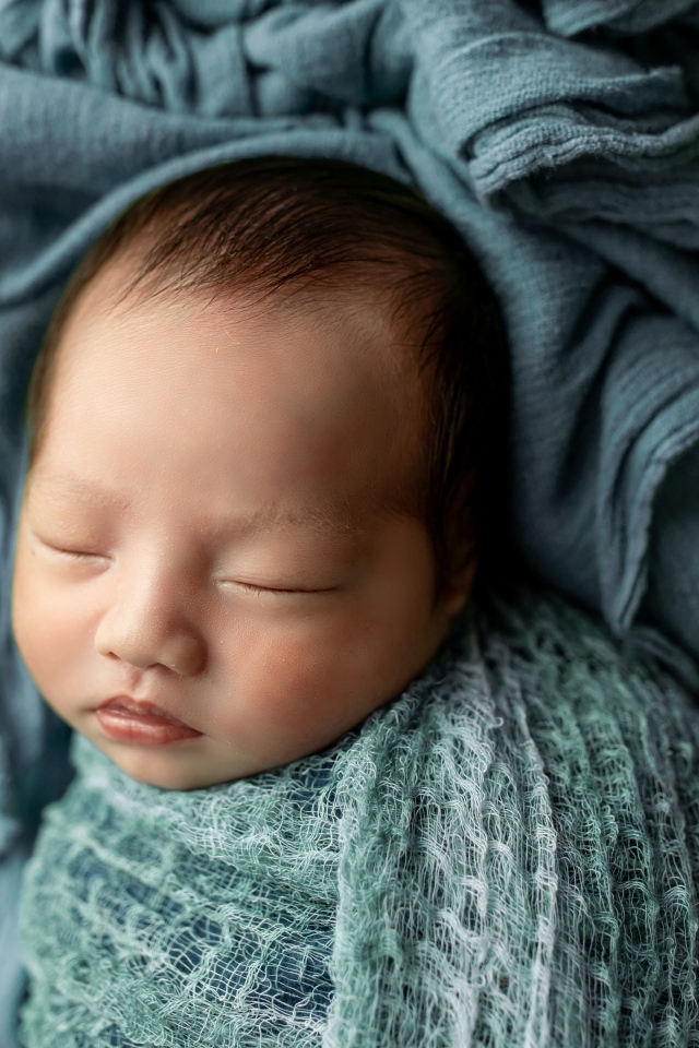 Новорожденный ребенок завернут в серое покрывало 