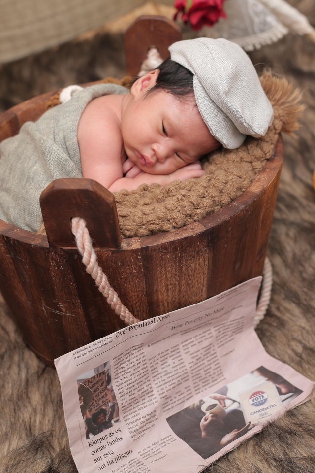 Новорожденный маленький мальчик в деревянном ведре на фотосессии 