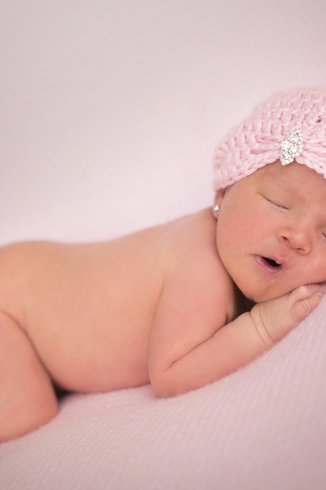 Розовая шапка на голове новорожденной девочки