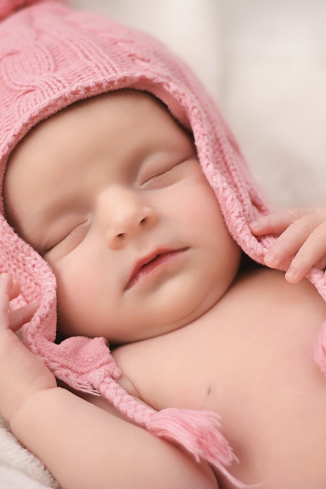 Розовая шапка на голове спящей малышки