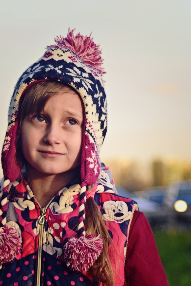 Грустная девочка в теплой шапке на улице