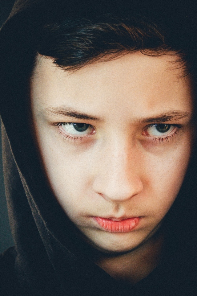 Серьезный мальчик в черном капюшоне