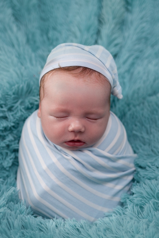 Спящий новорожденный малыш на голубом покрывале 