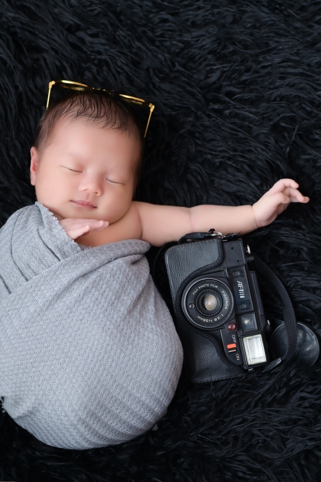 Спящий новорожденный малыш с фотоаппаратом