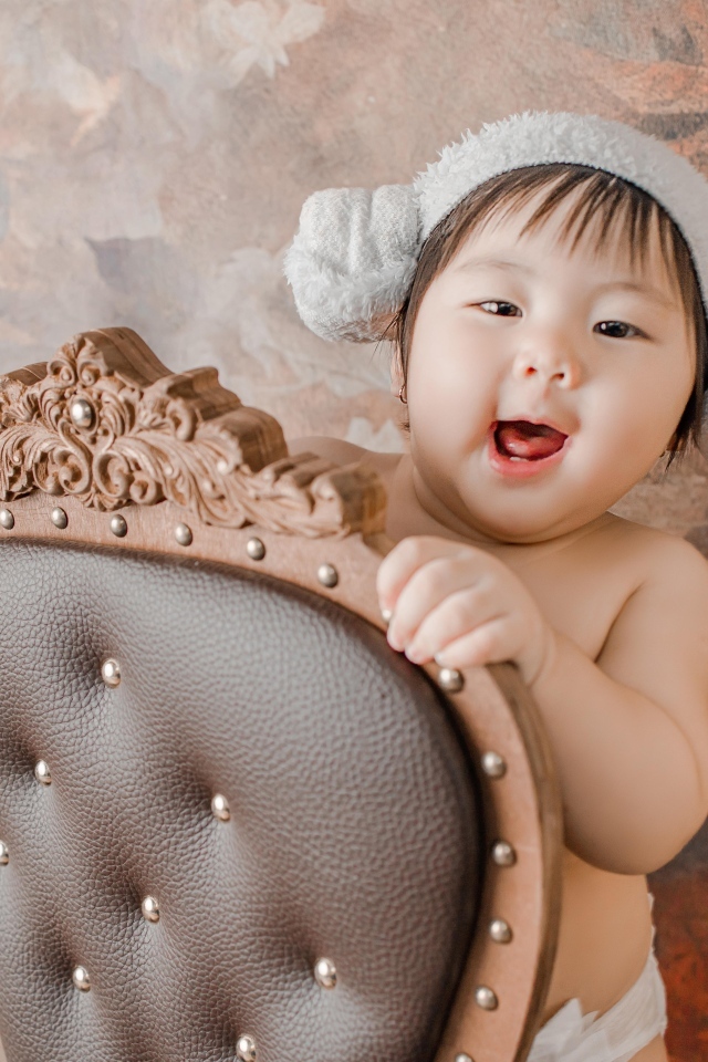 Улыбающийся ребенок азиат стоит у кресла