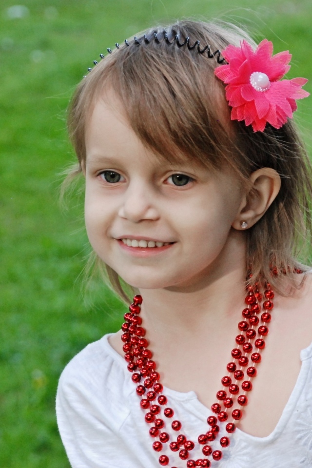 Улыбающаяся девочка стоит у дерева