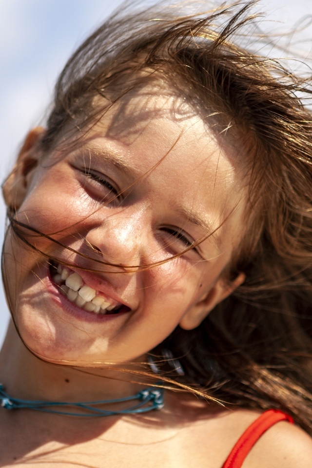 Улыбающаяся маленькая девочка стоит на ветру