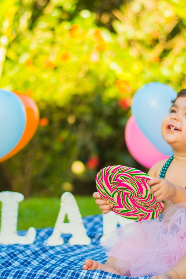 Улыбающаяся маленькая девочка с большой конфетой