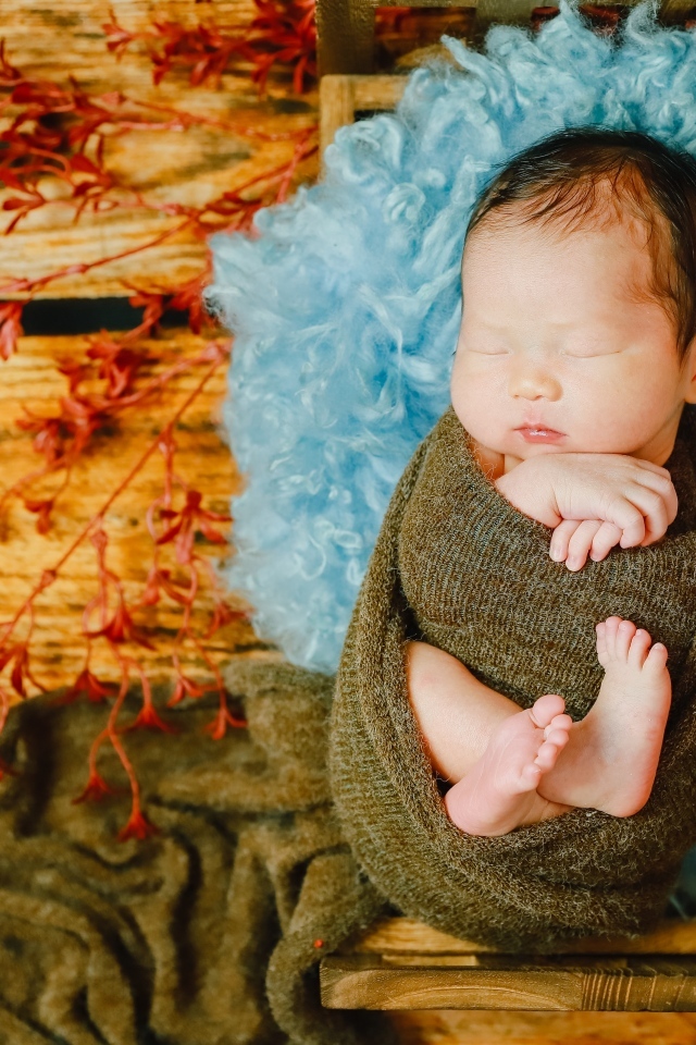 Крошечный новорожденный ребенок на голубой меховой подушке