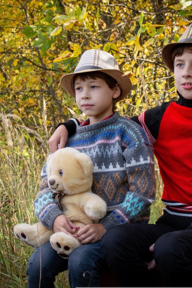 Два мальчика с игрушкой сидят у дерева