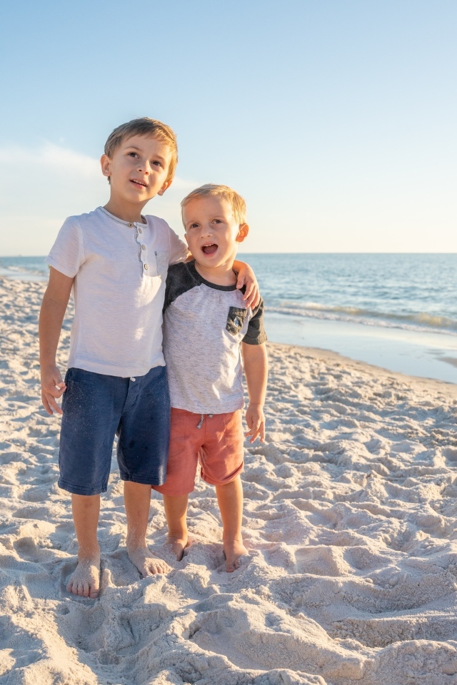 Два маленьких мальчика стоят на песке у моря