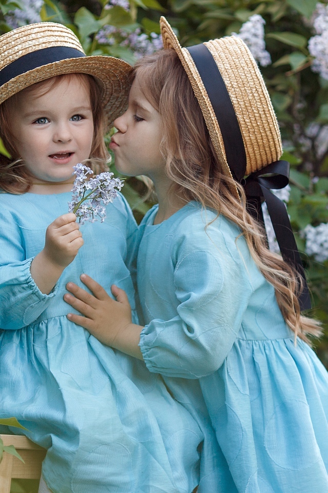 Две маленькие девочки в саду с сиренью