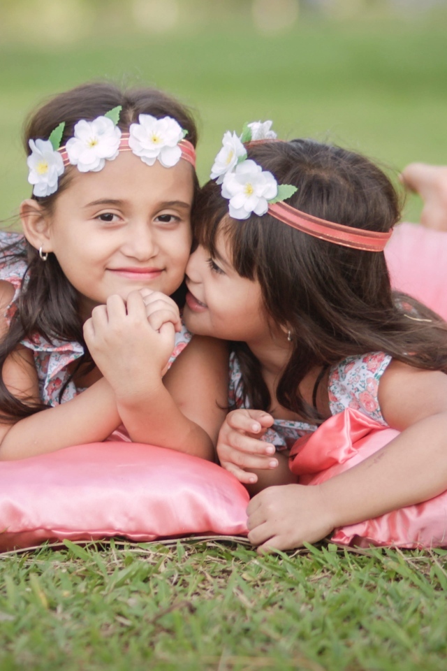 Две маленькие девочки лежат на подушках на траве