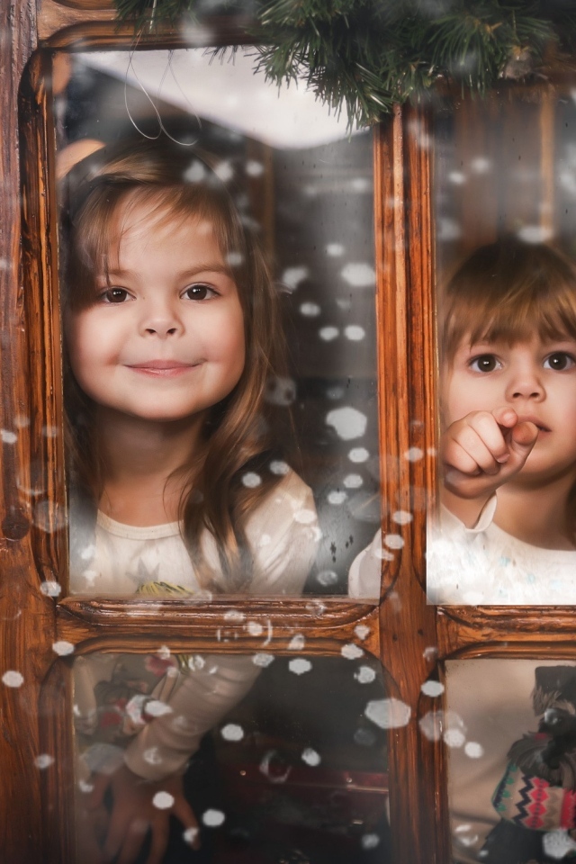 Две маленькие девочки сидят у окна на Рождество