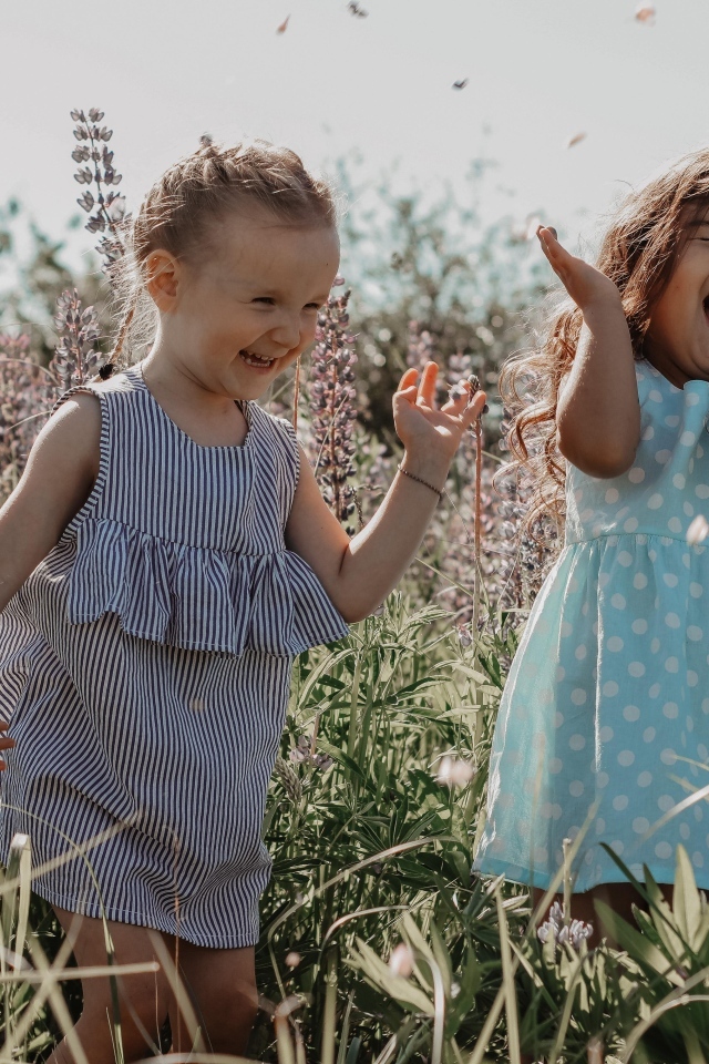 Две улыбающиеся маленькие девочки на поле с цветами