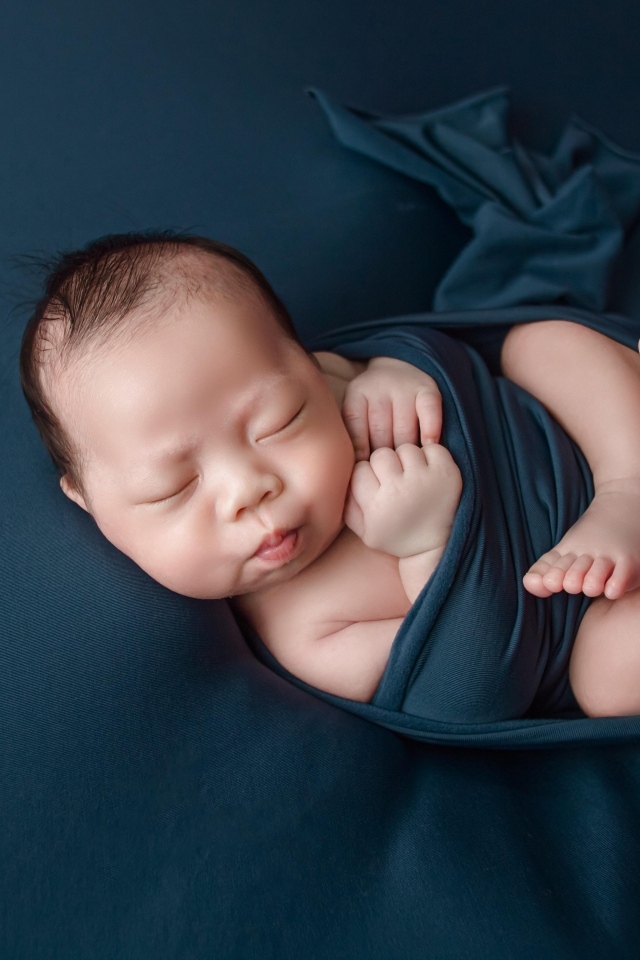 Новорожденный малыш в черном покрывале