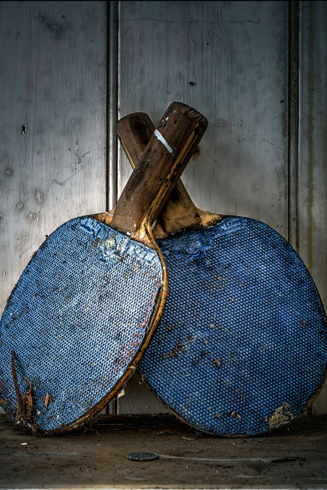 Две старые ракетки для настольного тенниса у стены