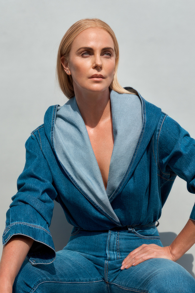 Актриса Шарлиз Терон в джинсовом костюме на сером фоне