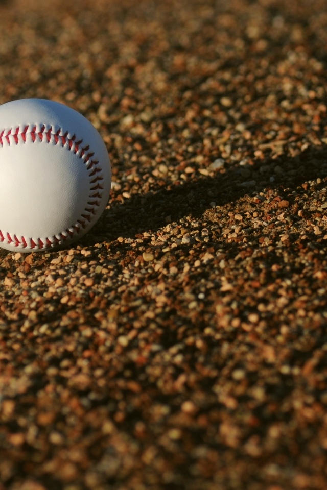 Бейсбольный мяч в лучах солнца на асфальте