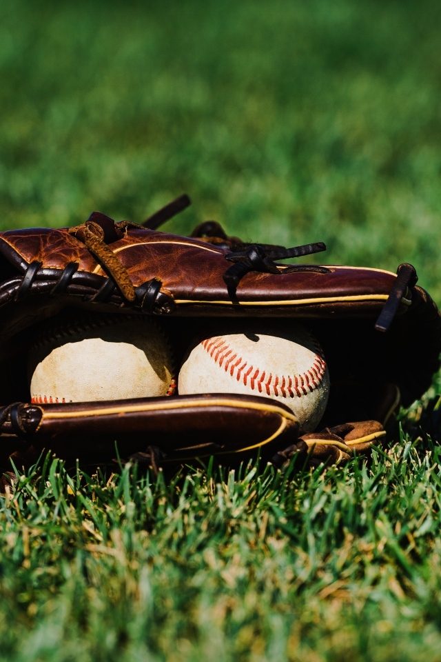 Бейсбольная перчатка и мячи на зеленой траве