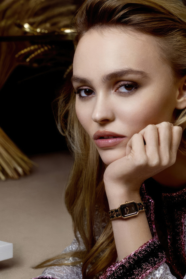 Милая девушка Лили-Роуз Депп сидит за столом